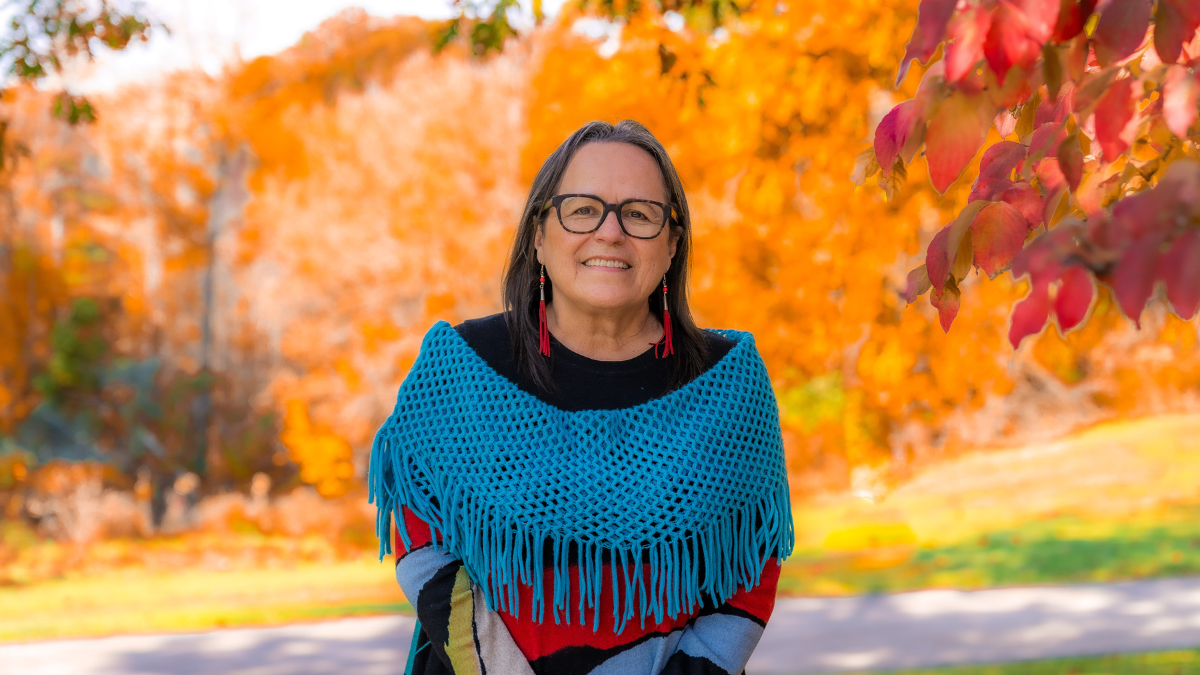 Bernice Downey, associate dean, Indigenous Health, standing outside with fall foliage in the background.