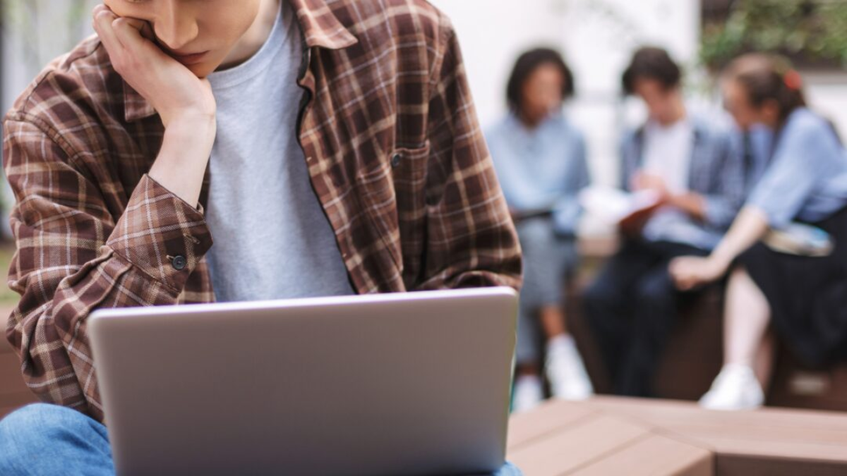 A young adult sitting with his laptop.